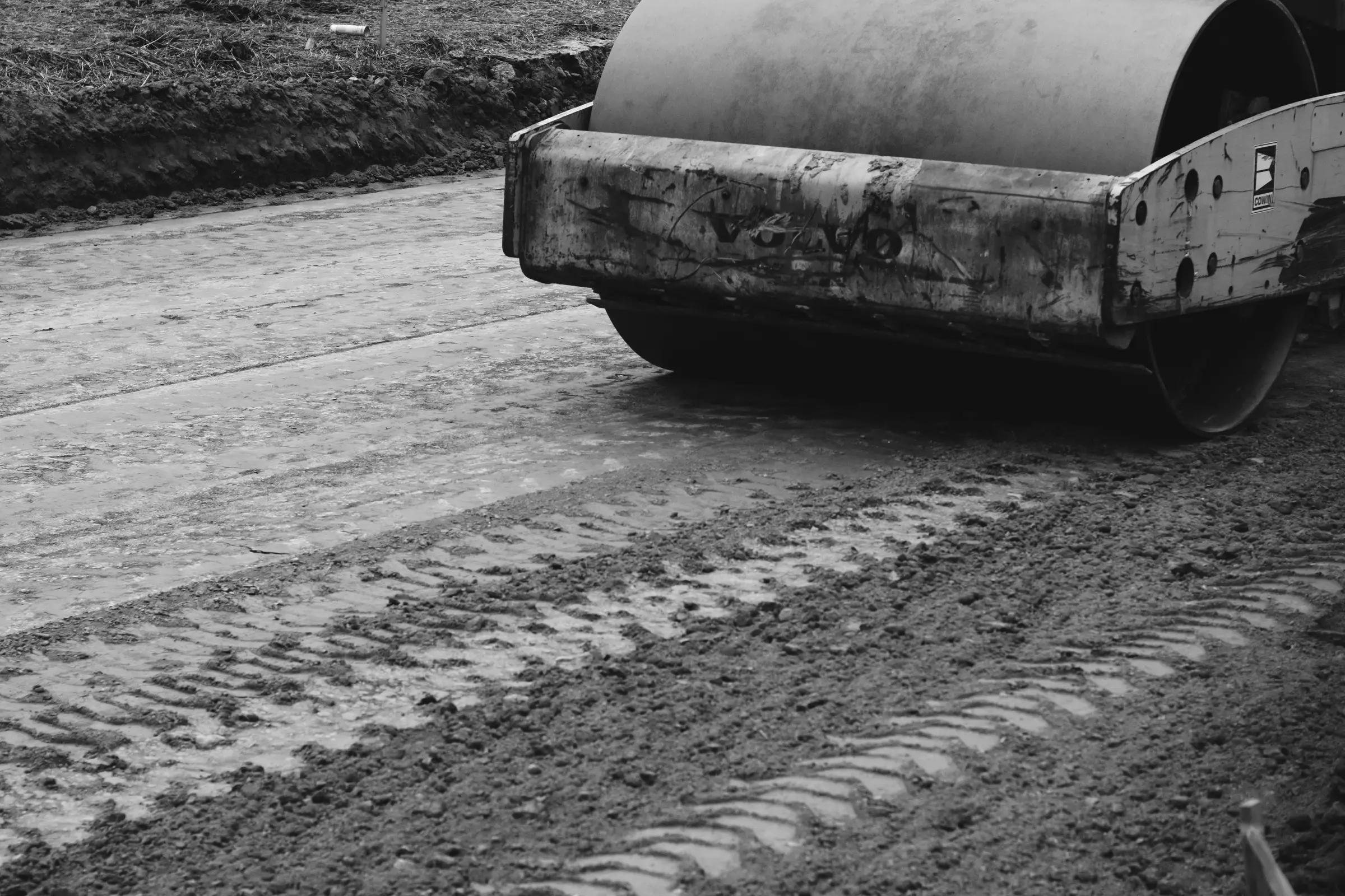 Black and white close-up of a road roller on freshly laid gravel